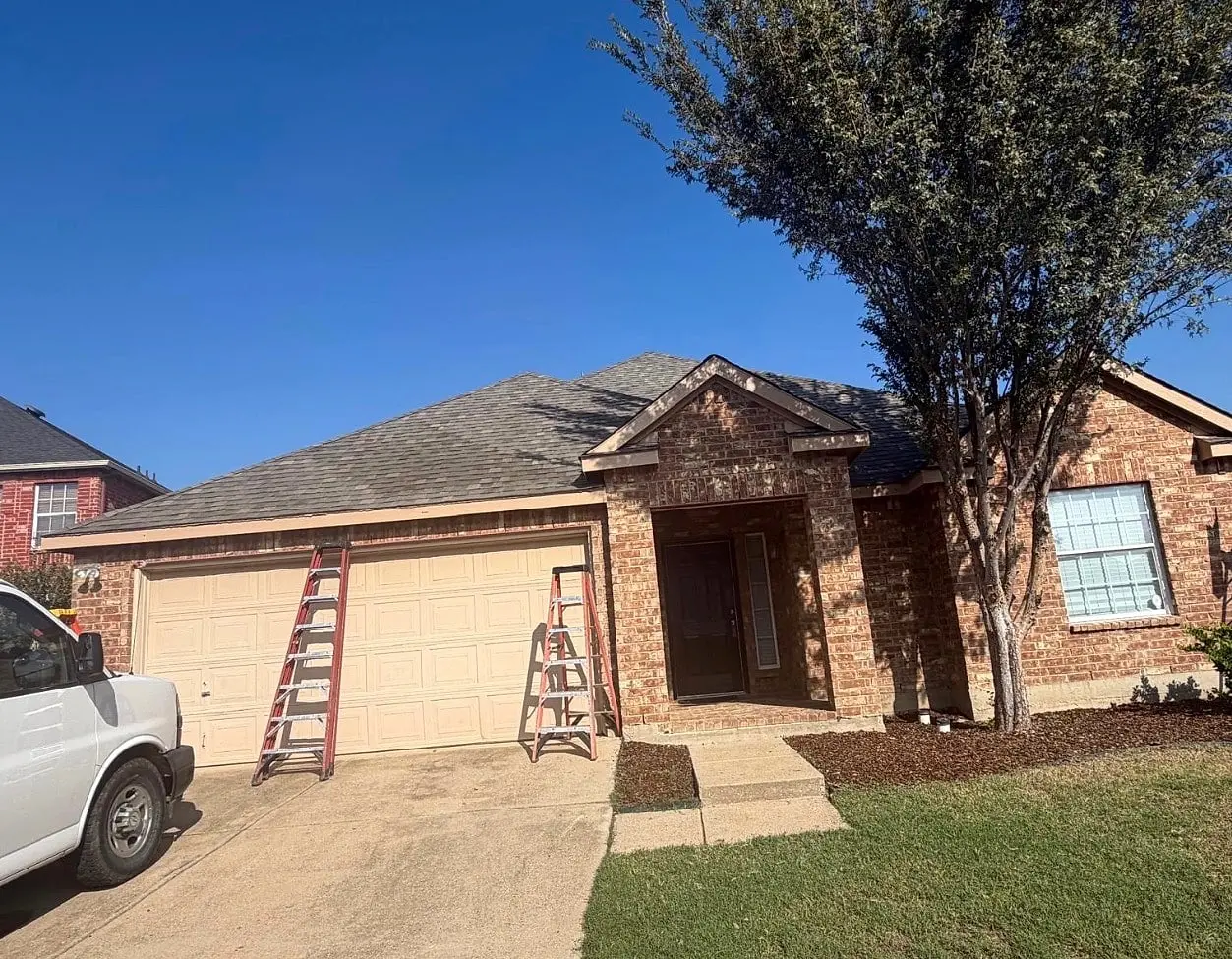 Front of a brick home before gutters, ladders set up