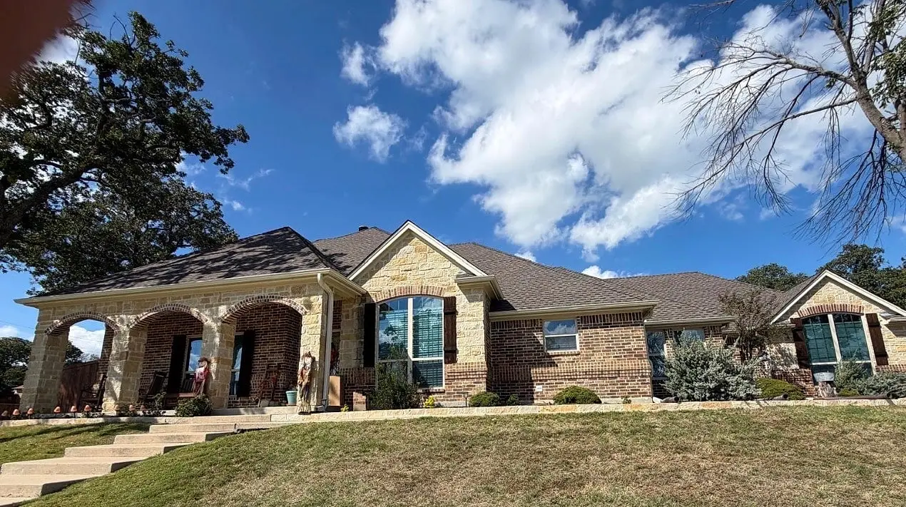 The finished stone home with new gutters along every roofline
